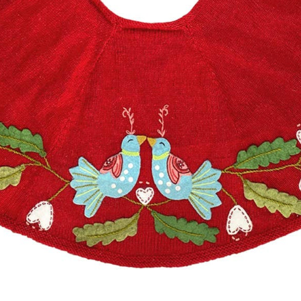 Red tree skirt with embroidered birds and leaves on a white background