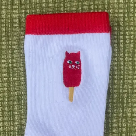 White sock with red accents and a cartoon character on a green textured background