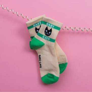 Beige and green socks with 'Baby Cats' text on a pink background