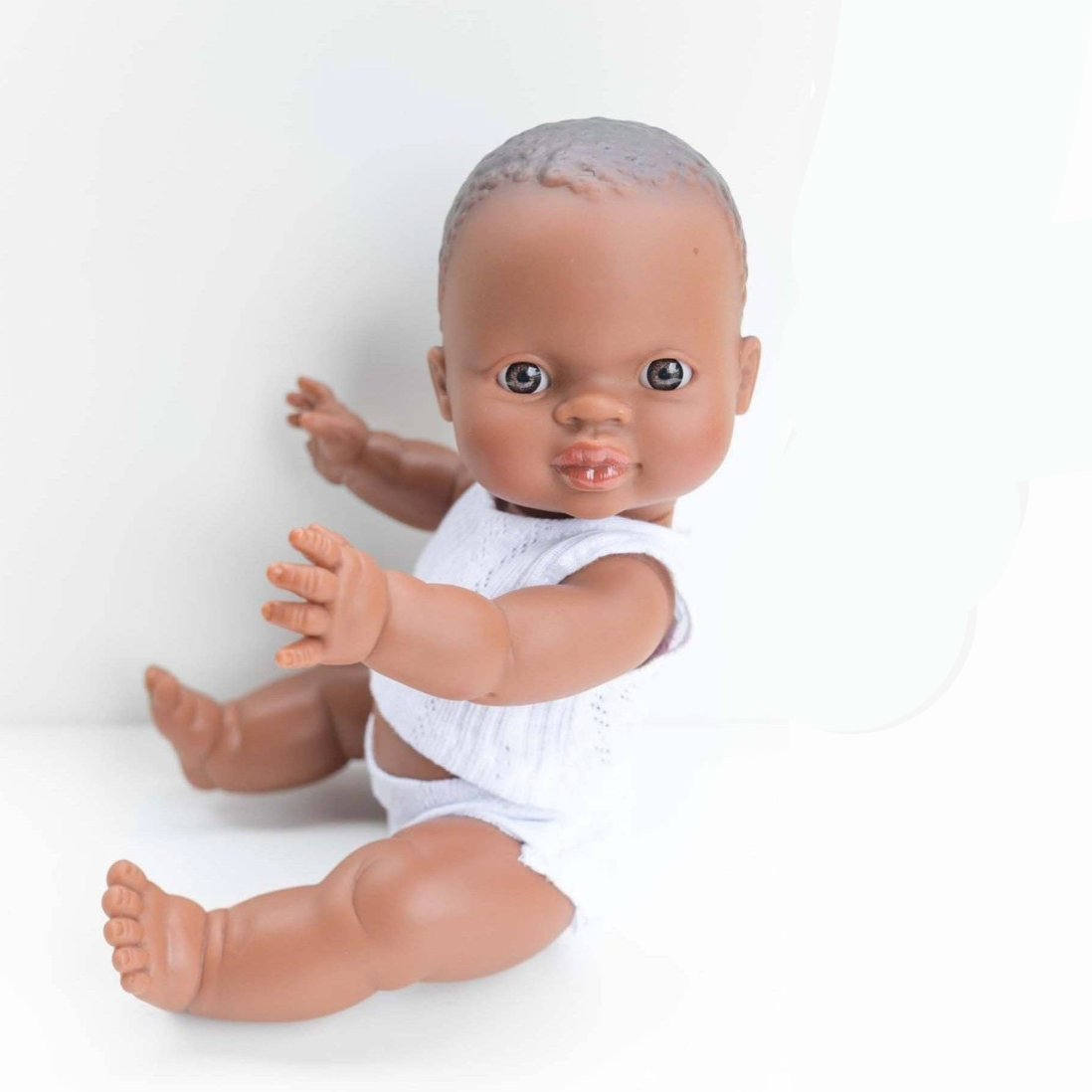 Baby doll in a white outfit on a white background