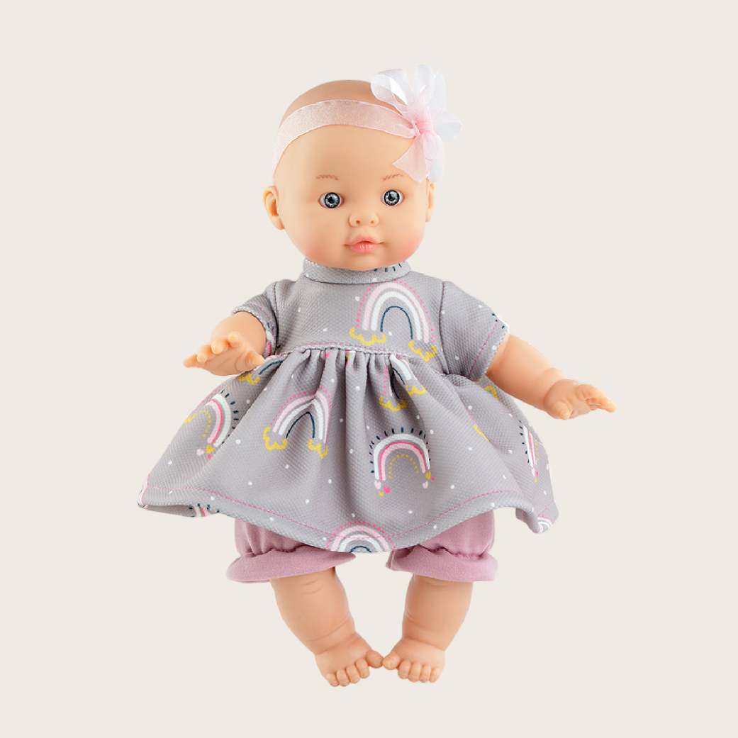 Doll wearing a gray dress with rainbow patterns on a white background