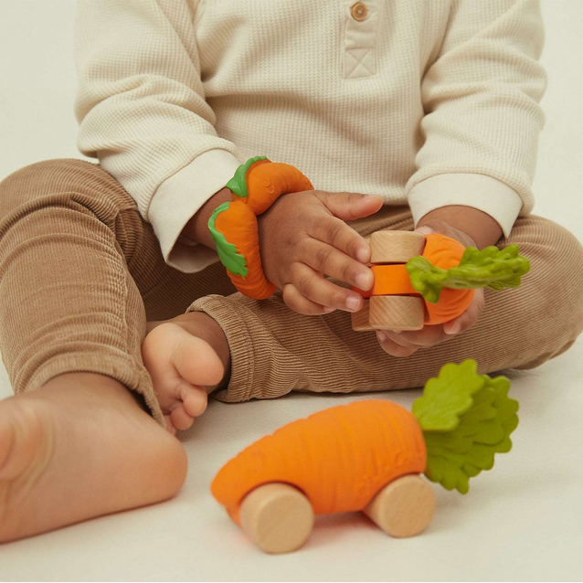 Child playing with carrot-shaped toys on a light background