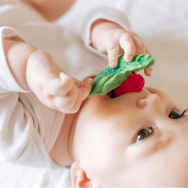Baby playing with a green and red teething toy