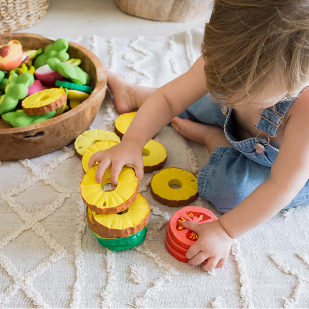 Child playing with colorful rubber toys on a textured surface