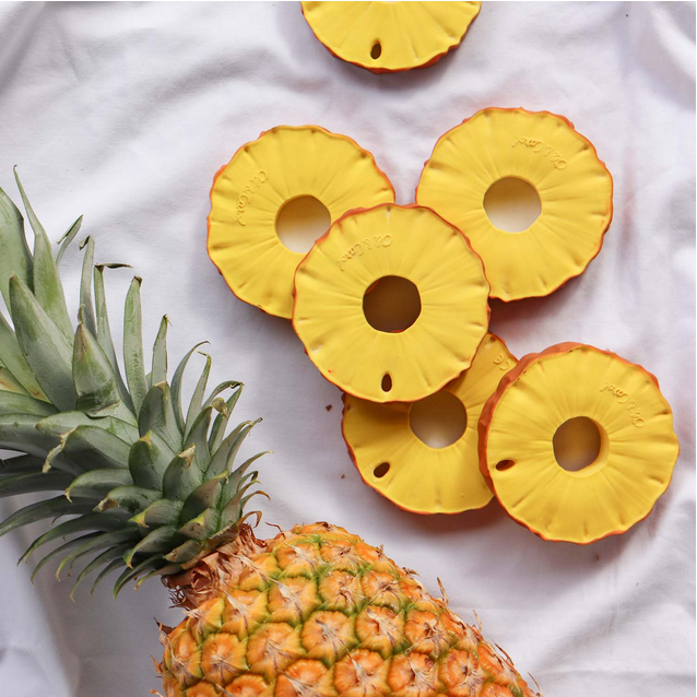 Rubber Pineapple slices and whole pineapple on a white fabric background