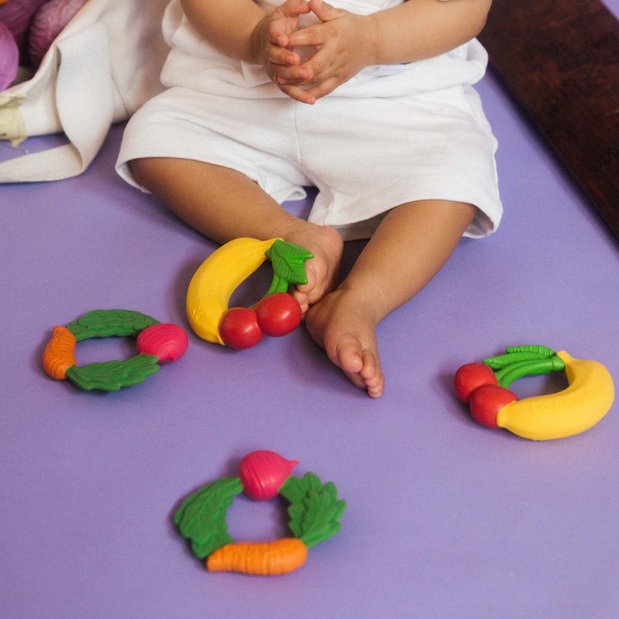 Child playing with colorful vegetable-shaped toys on a purple surface