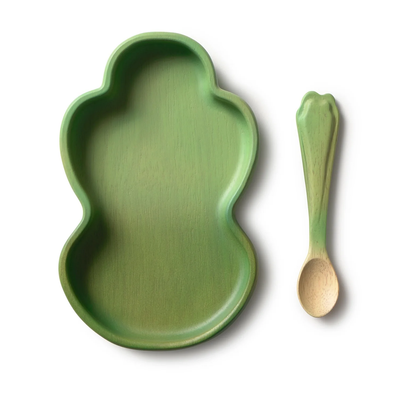 Green leaf-shaped plate and wooden spoon on a white background