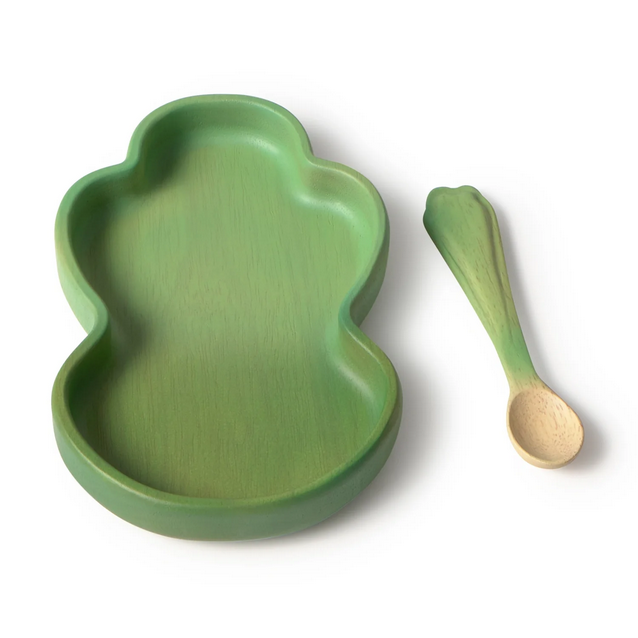 Green leaf-shaped plate and wooden spoon on a white background