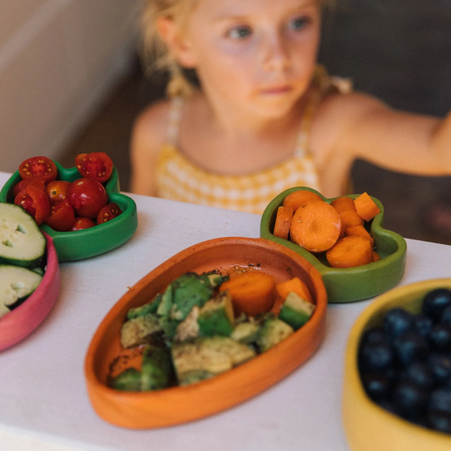 Colorful toy vegetables on a table with a child in the background