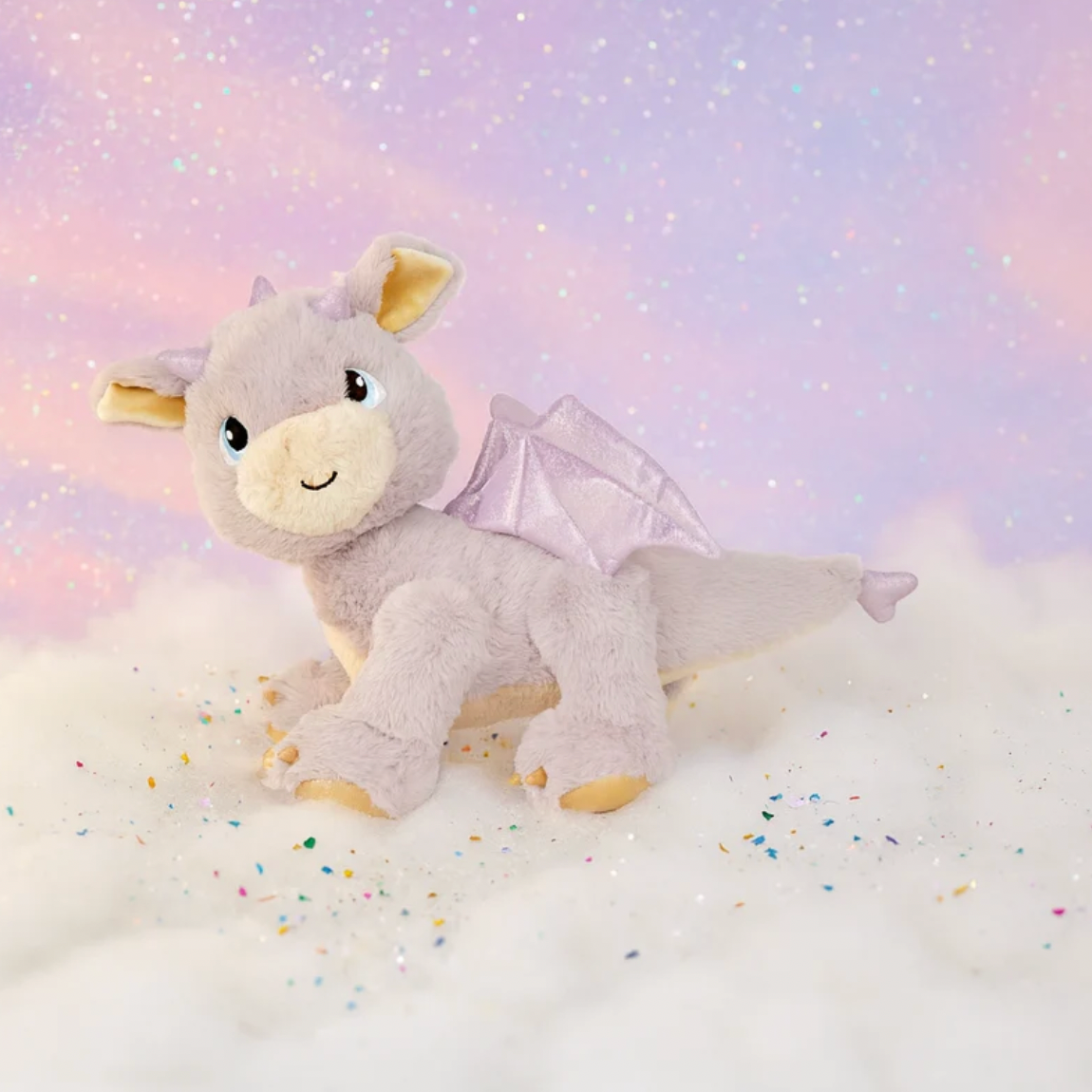Plush dragon toy on a soft, cloud-like surface with a pastel gradient background