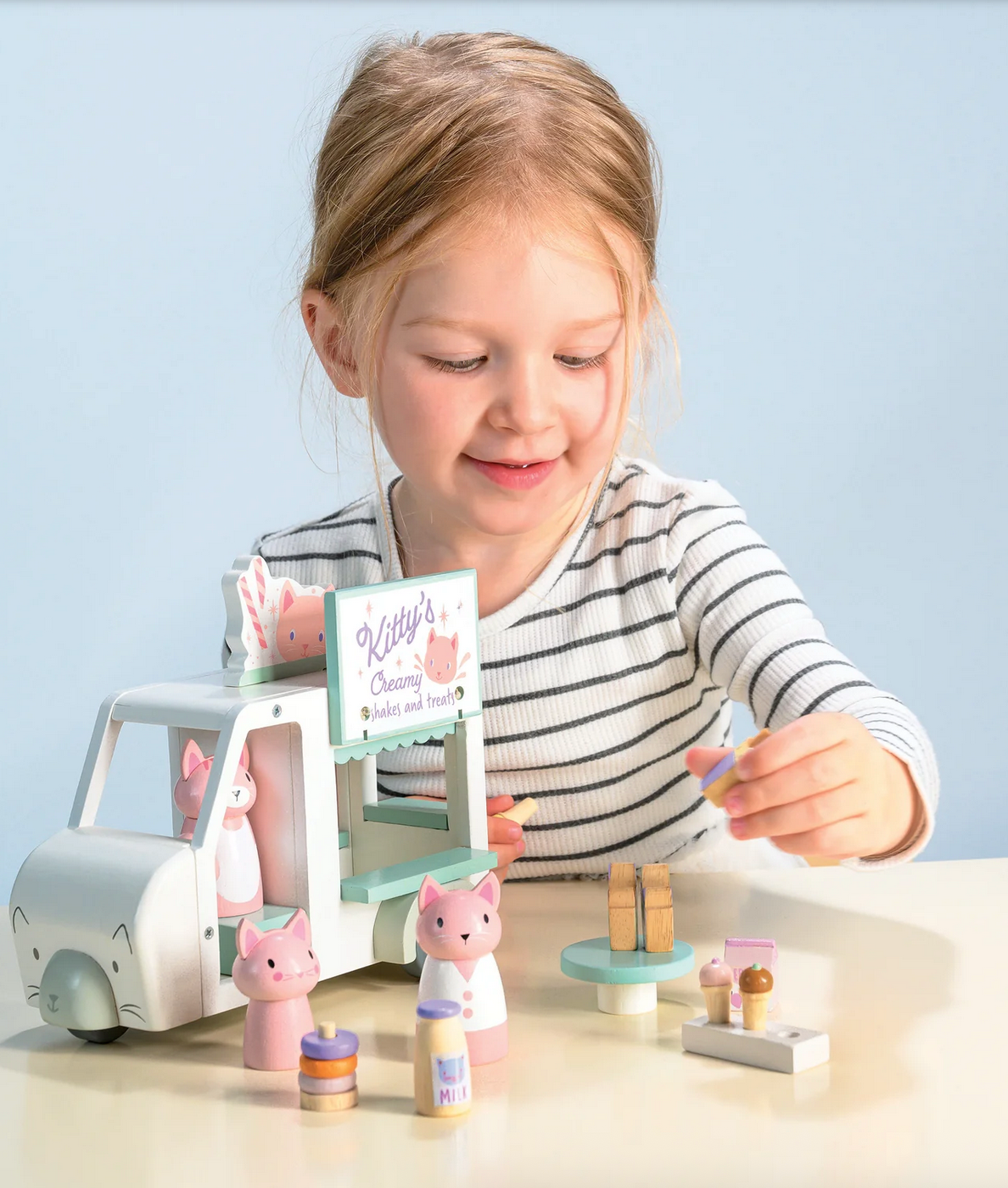 Child playing with a toy set on a table against a light blue background