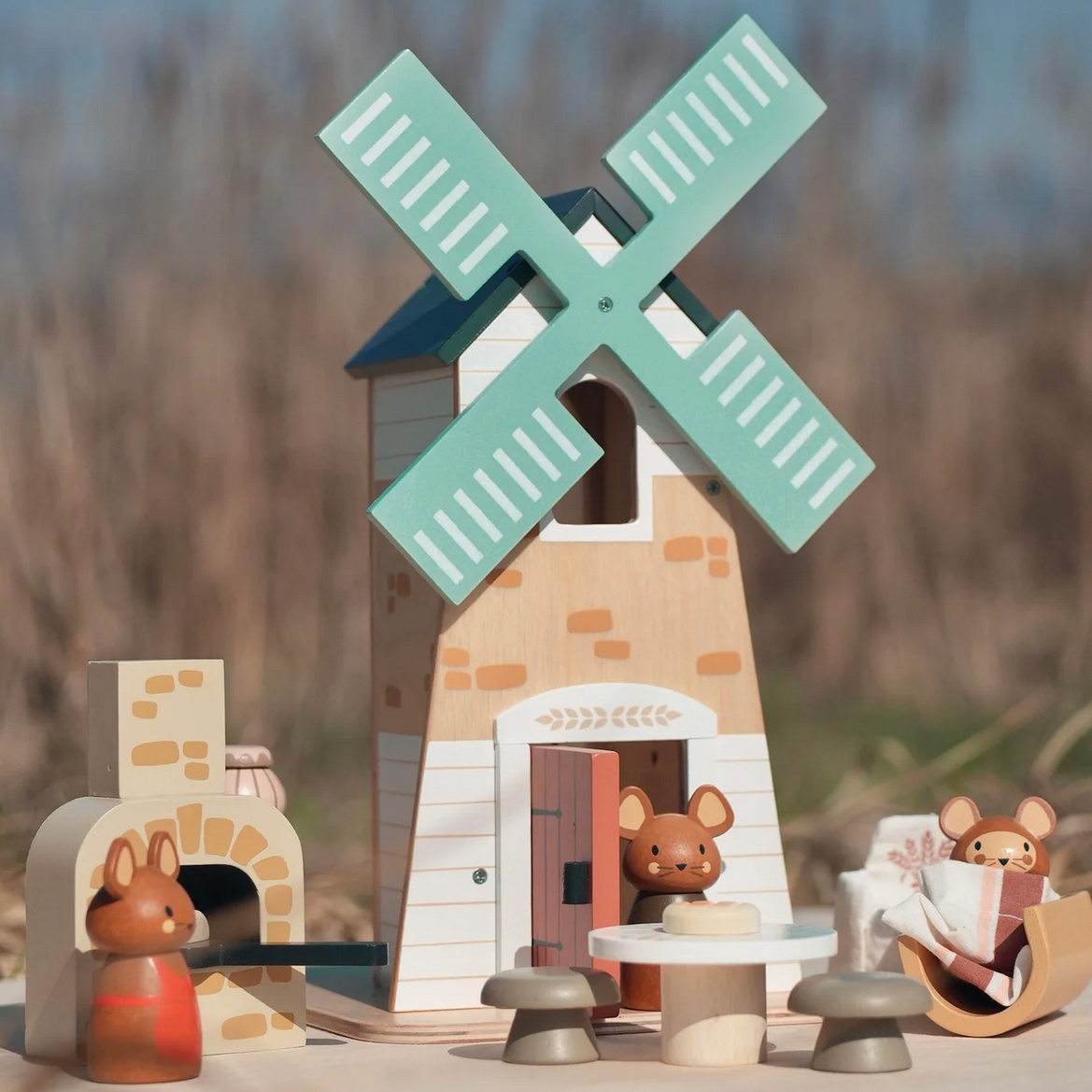 Toy windmill with mice figures on a blurred natural background