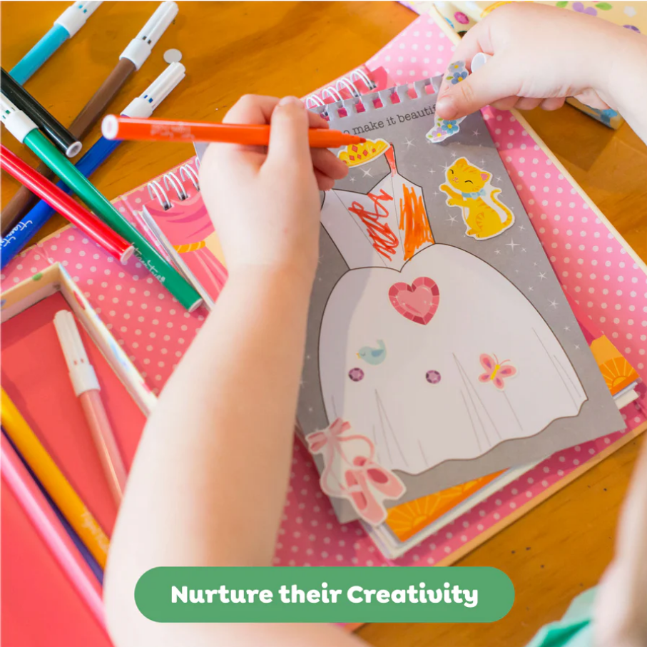 Child coloring a picture with markers on a wooden table, surrounded by art supplies.