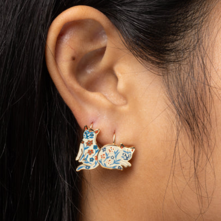 Floral cat-shaped earrings worn by a person