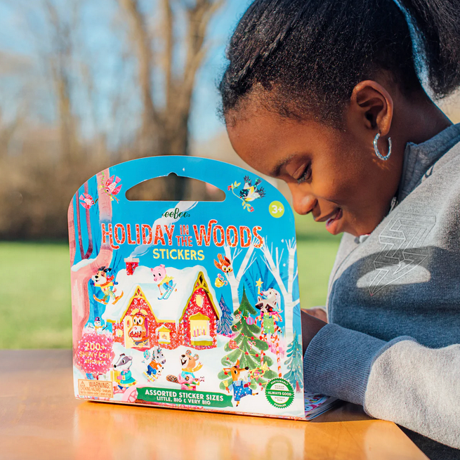 Child looking at a 'Holiday Woods Stickers' package outdoors