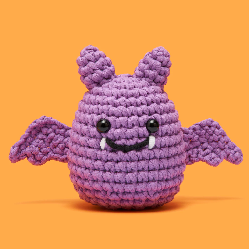Purple knitted creature with bat wings on an orange background