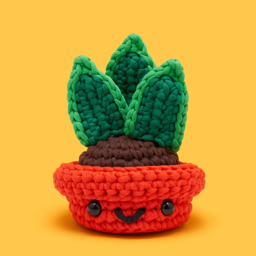 Crocheted succulent plant in a pot with a yellow background