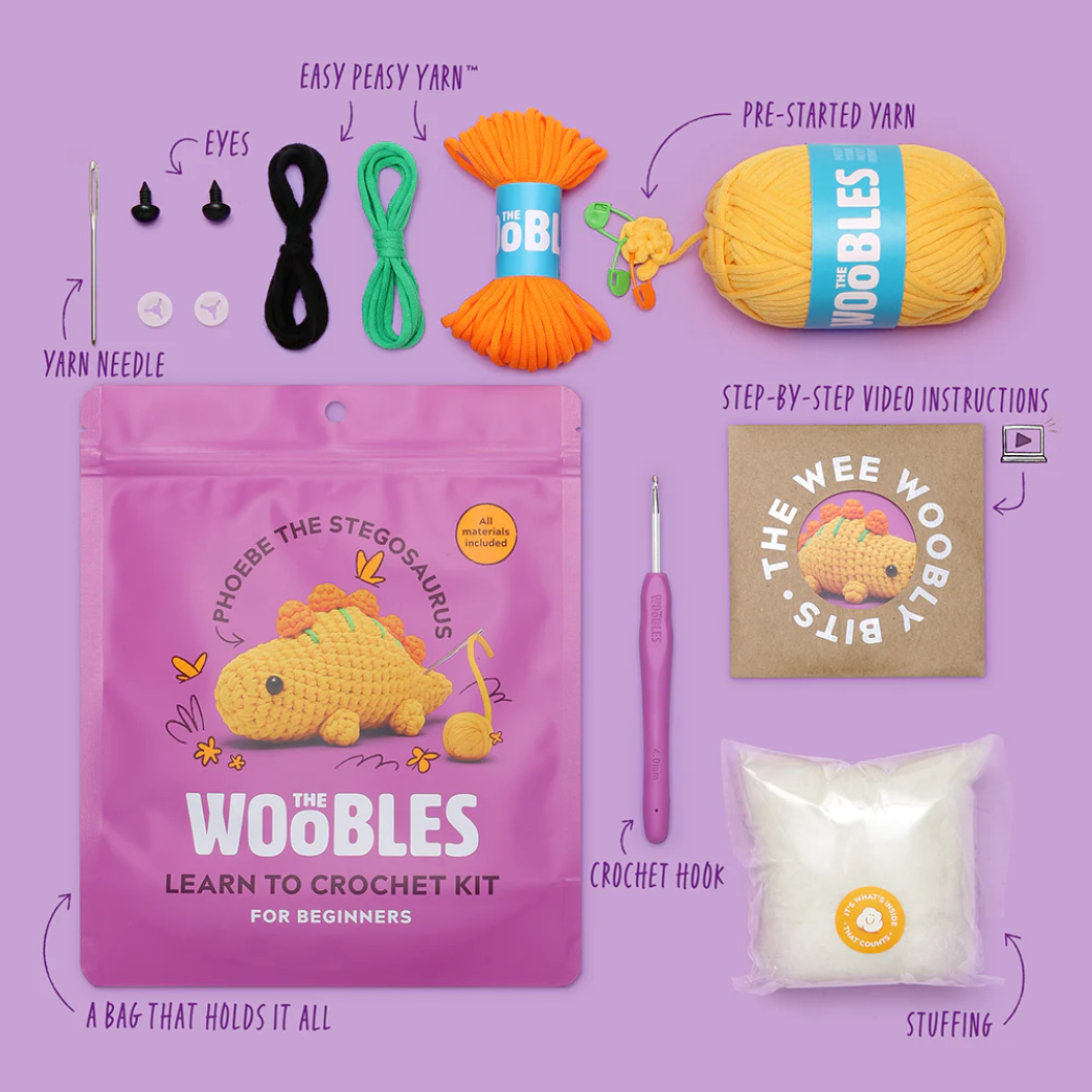Woobles learn to crochet kit with packaging, yarn, hook, and stuffing on a purple background