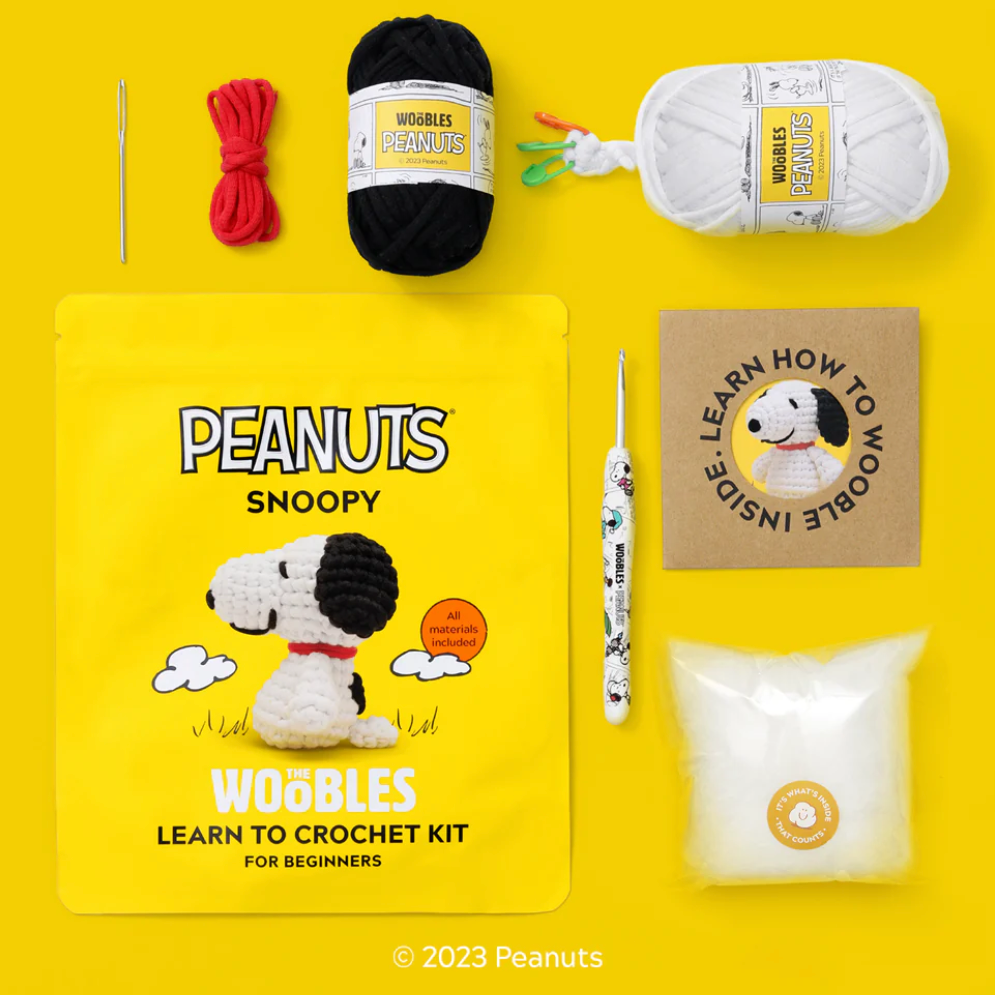 Peanuts Snoopy crochet kit with yarn, hooks, and instructions on a yellow background
