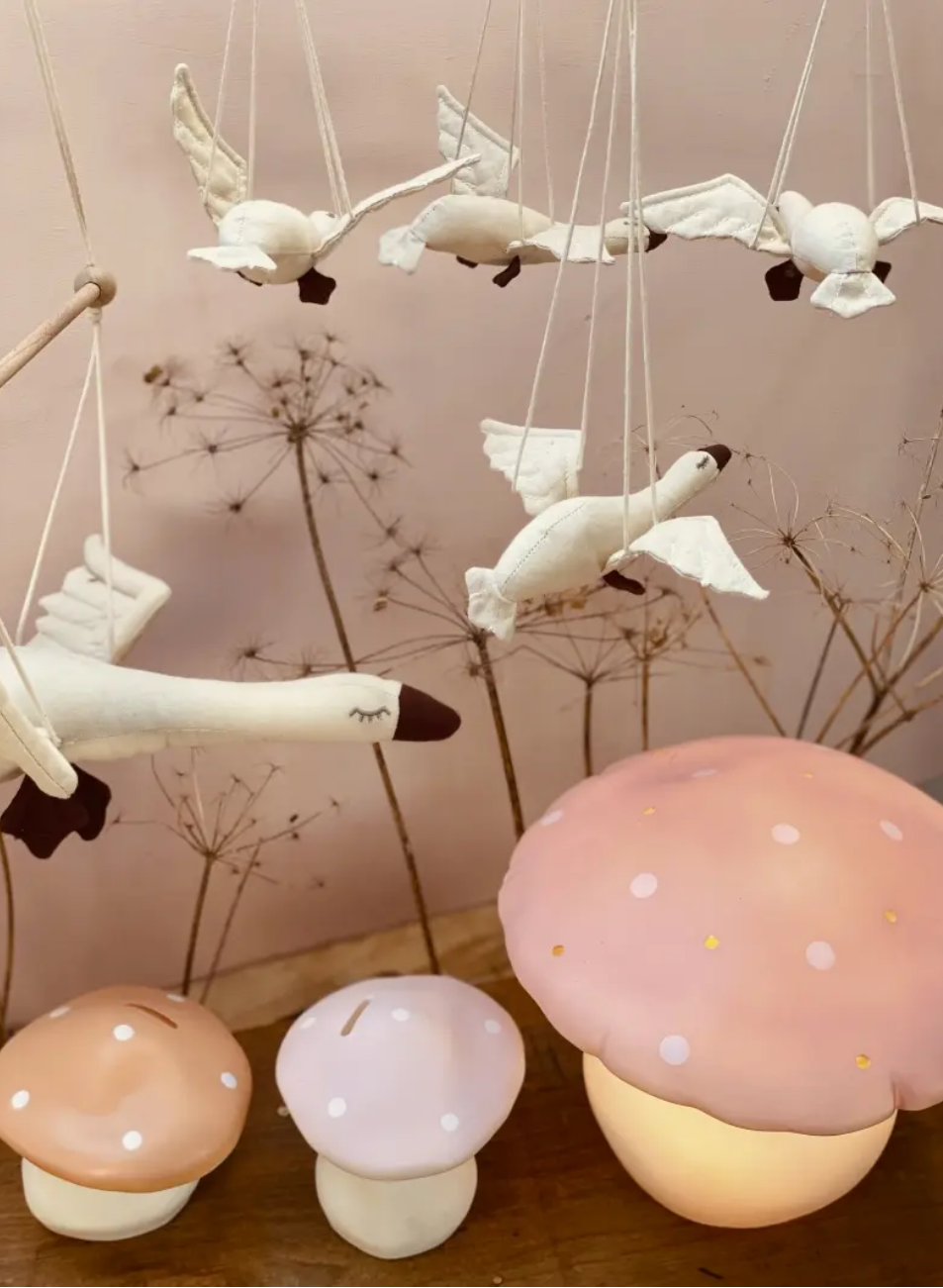 Decorative mushroom lights with swan-shaped candles on a wooden surface.