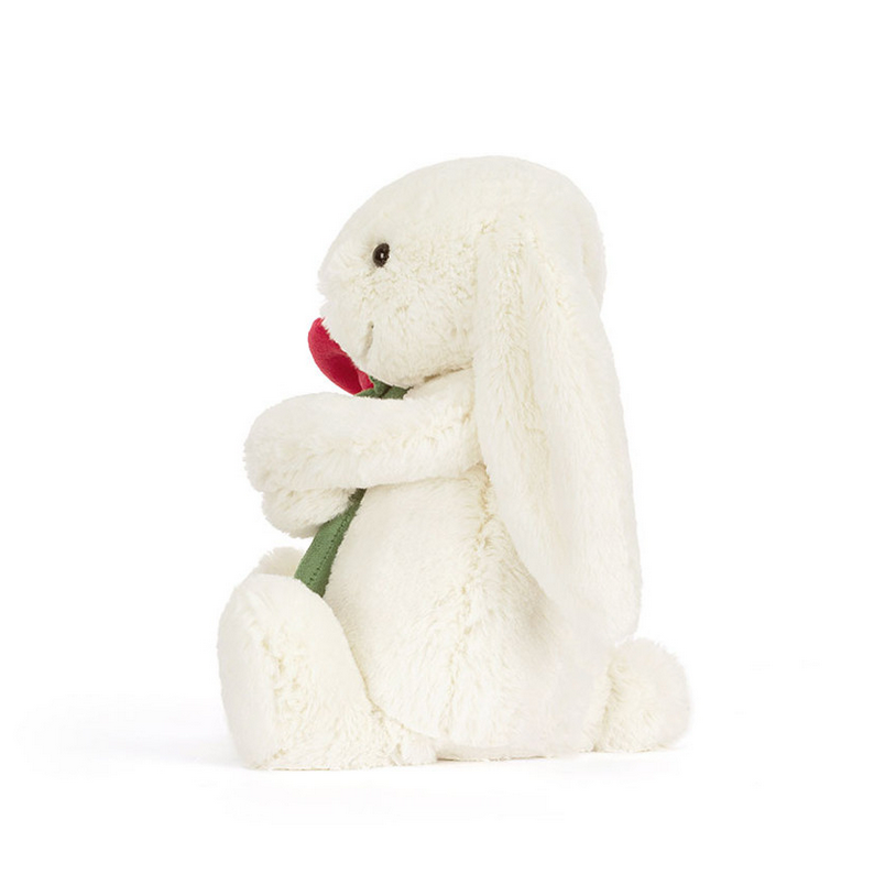 White plush bunny holding a red heart on a white background