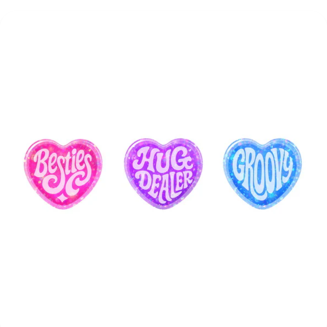 Three heart-shaped toys with 'Besties', 'Hug Dealer', and 'Groovy' text in colorful fonts on a white background.