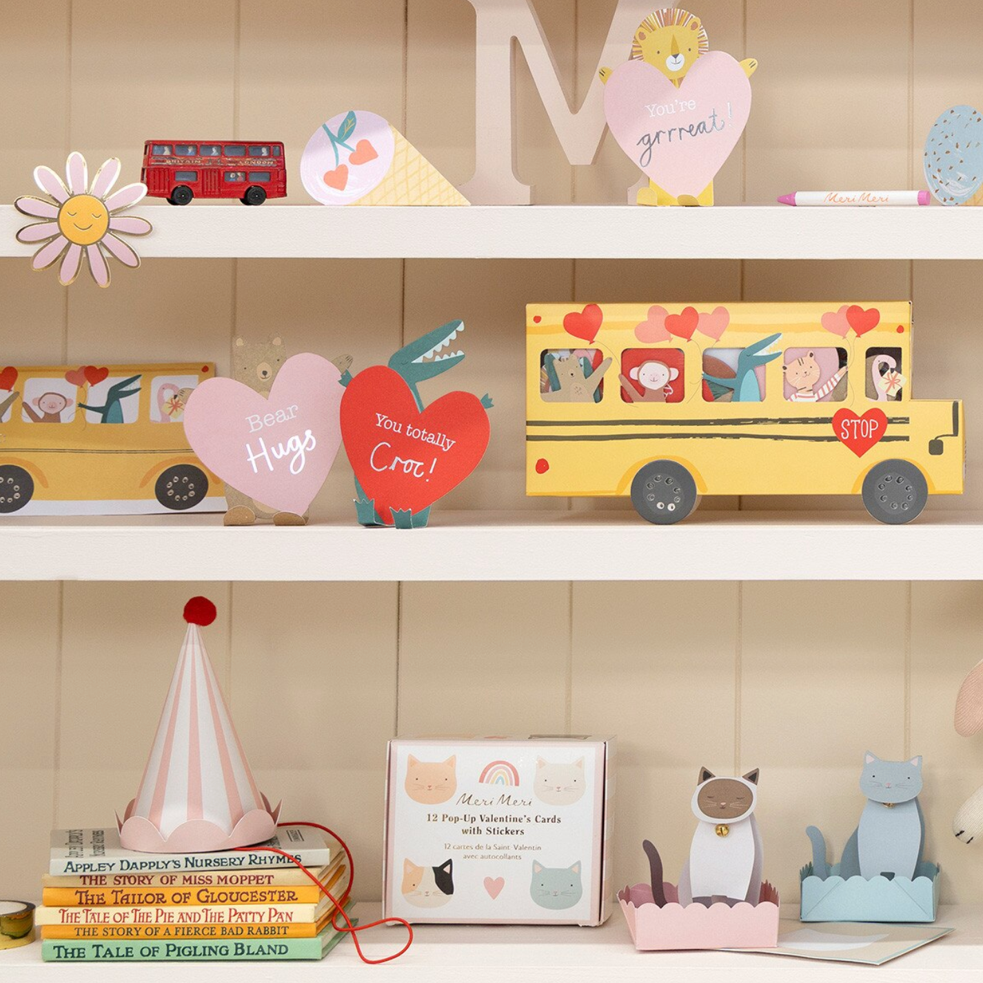 Shelf with decorative items including a yellow bus, heart-shaped signs, and books.
