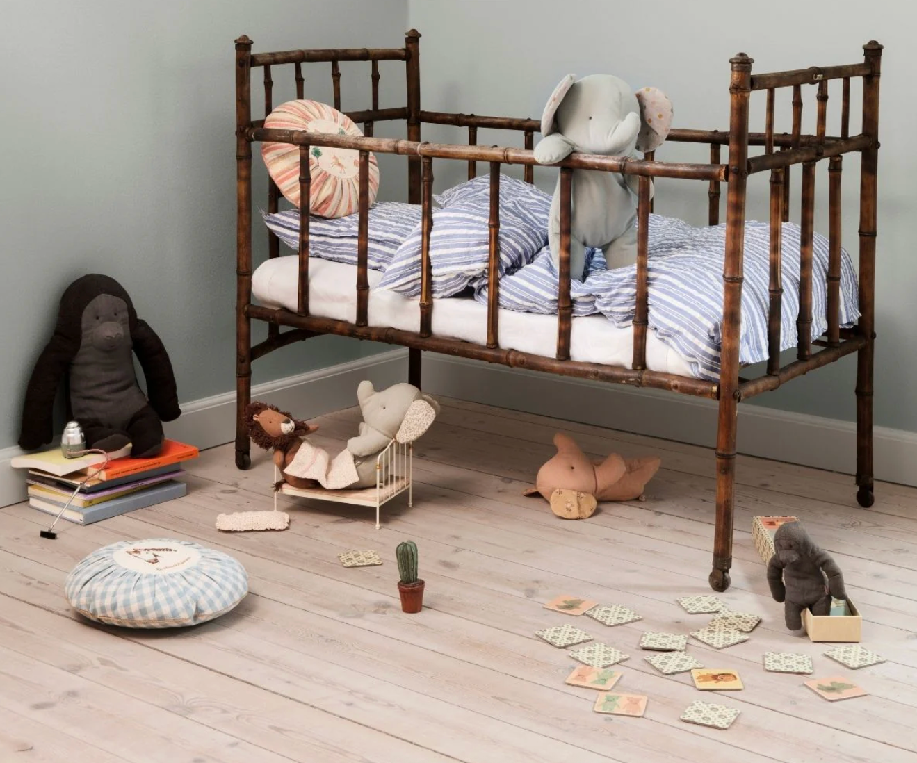 Children's room with wooden crib, toys, and books on a light wooden floor.