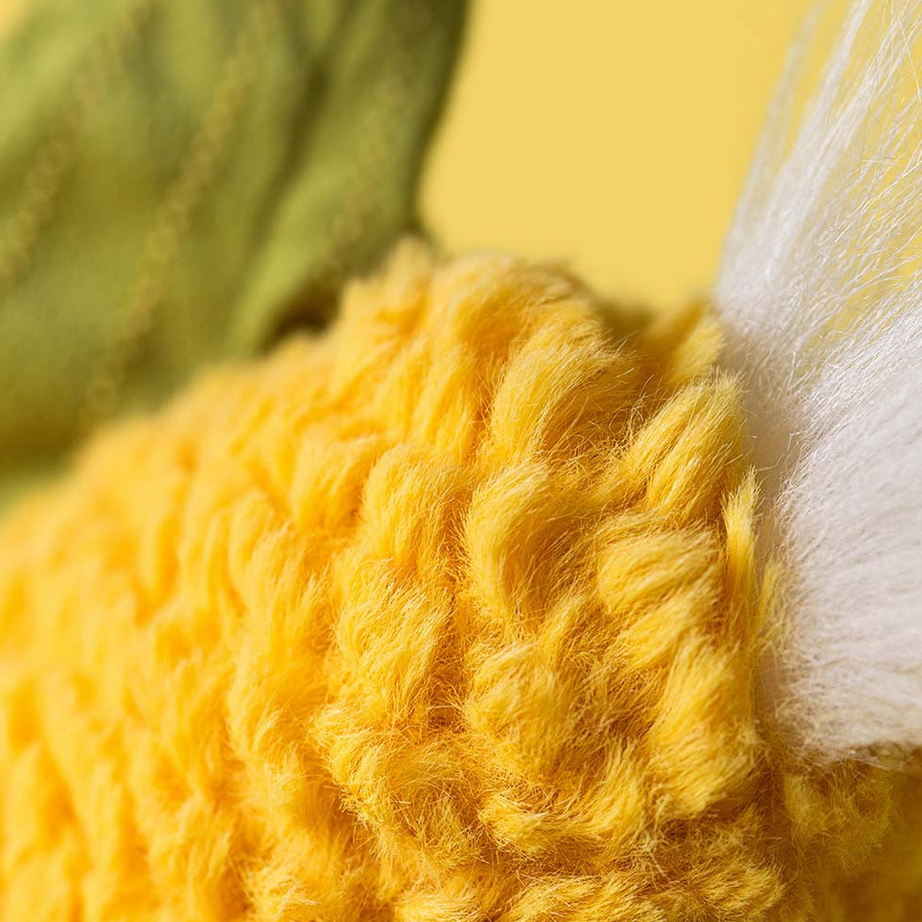 Close-up of yellow yarn with a white fluffy object in the background