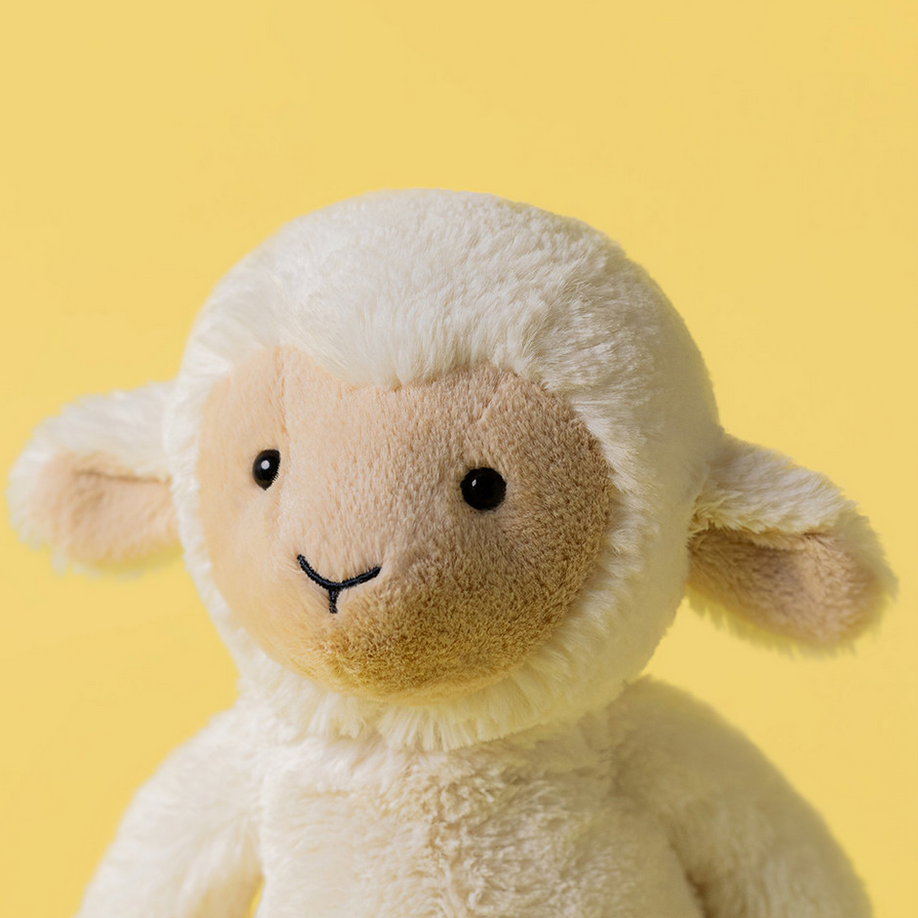 Stuffed lamb toy with a yellow background