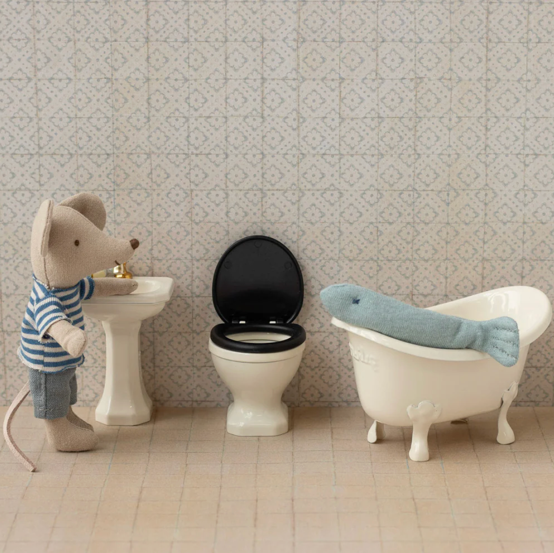 Toy mouse in a bathroom setting with sink, toilet, and bathtub.