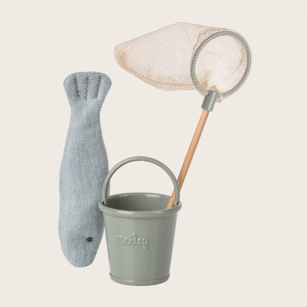 Gray toy fish, bucket, and net on a light beige background