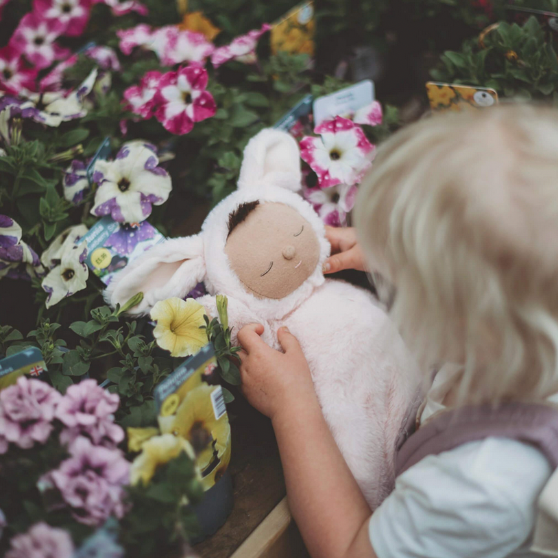 Child playing with a plush toy surrounded by flowers