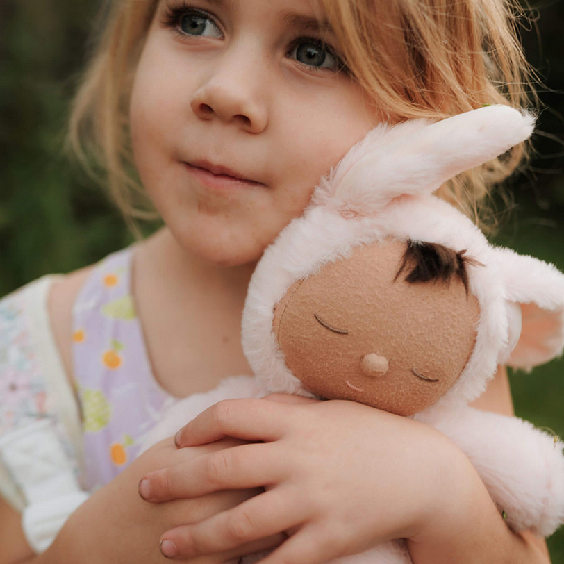 Child holding a soft toy with a blurred natural background