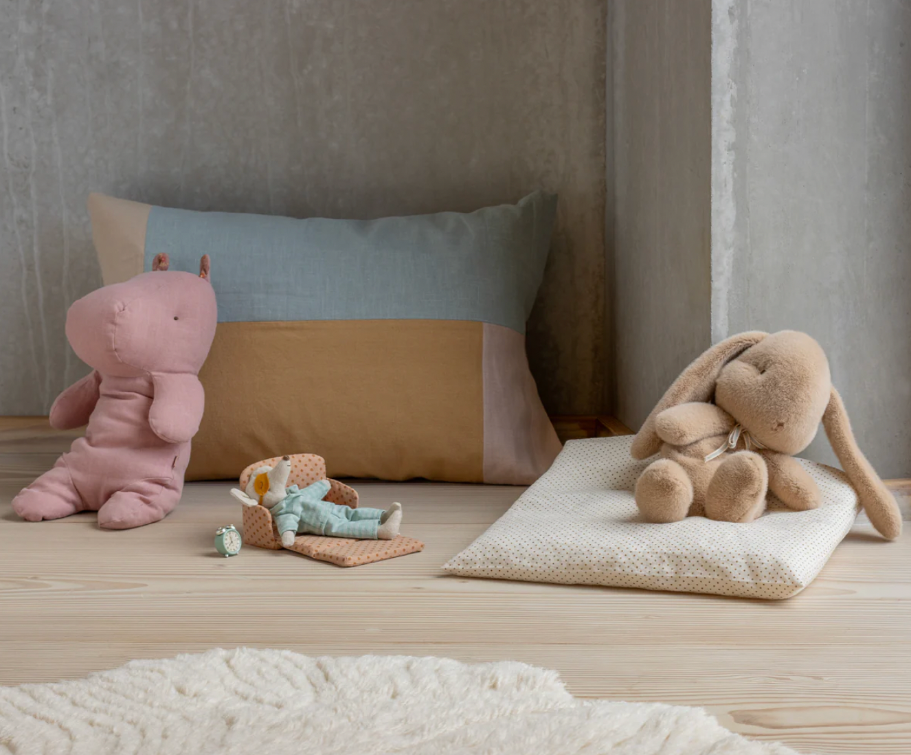 Children's room with plush toys on a wooden floor against a neutral wall.