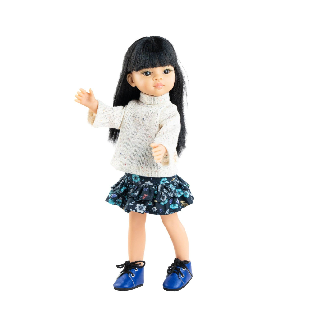 Doll with long black hair, white shirt, and floral skirt on a white background