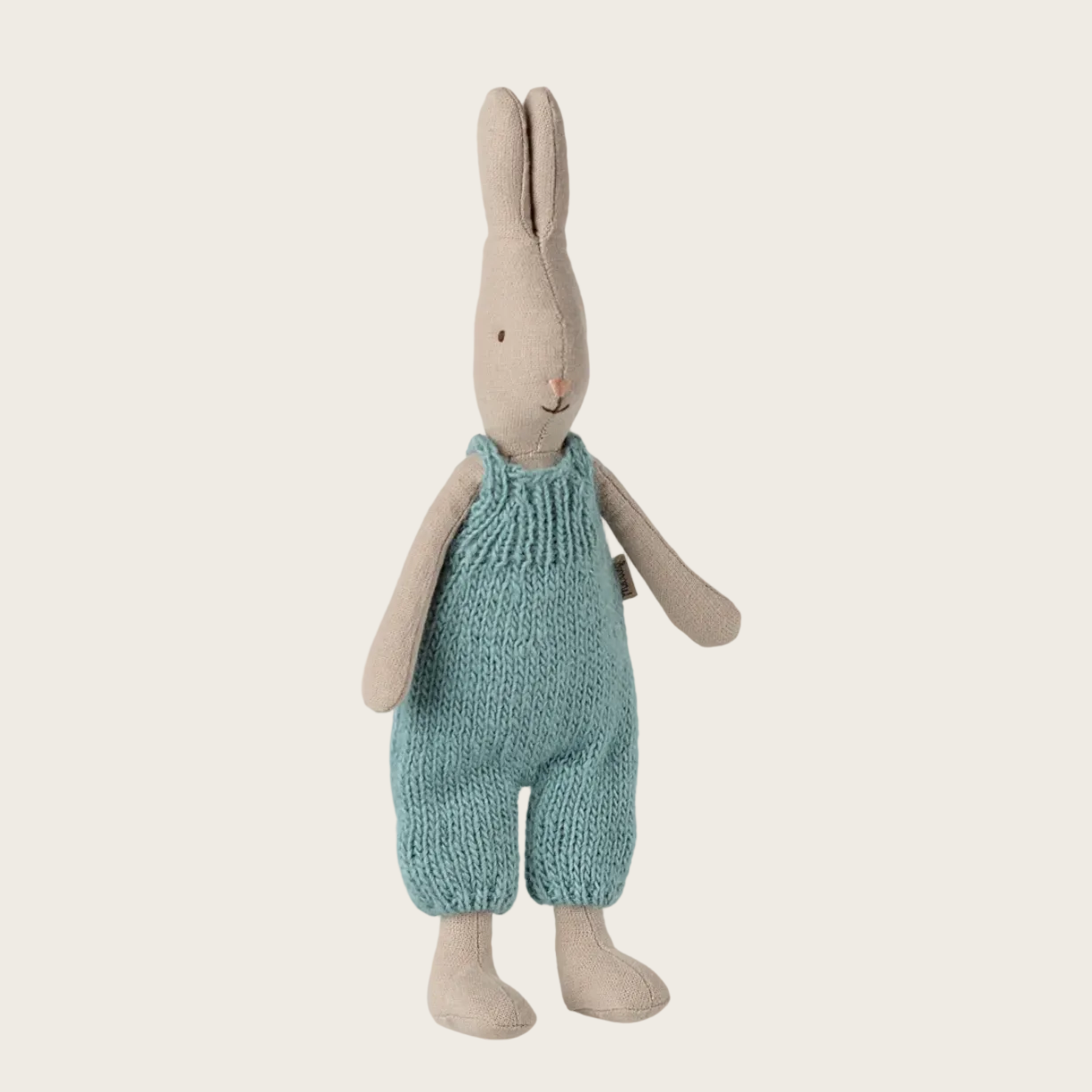 Stuffed rabbit toy with a knitted outfit on a beige background