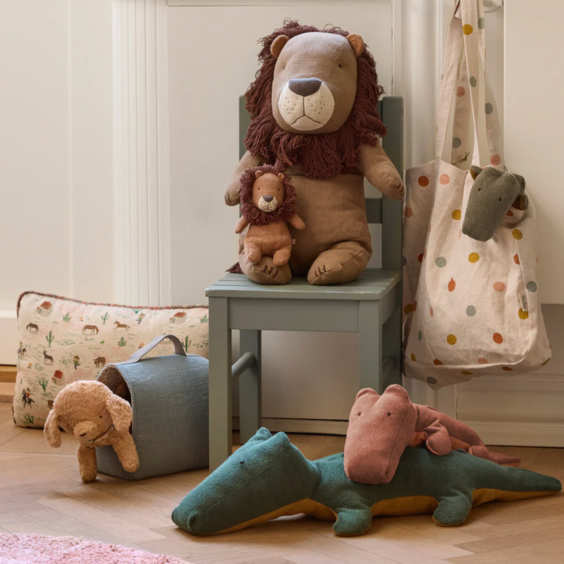 Children's room with plush toys including a lion, bear, and alligator on a wooden floor.