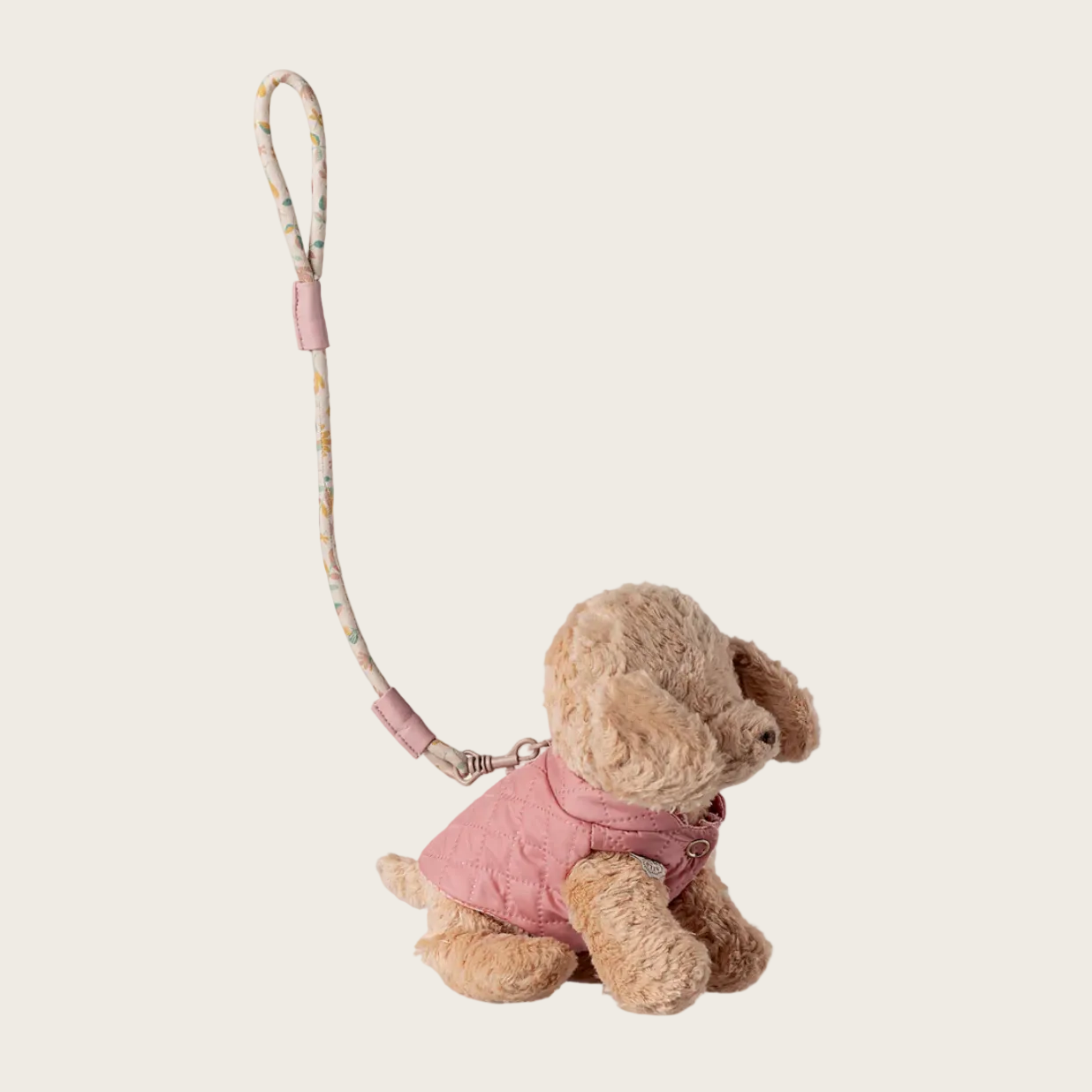 plush dog with a pink outfit and leash on a white background