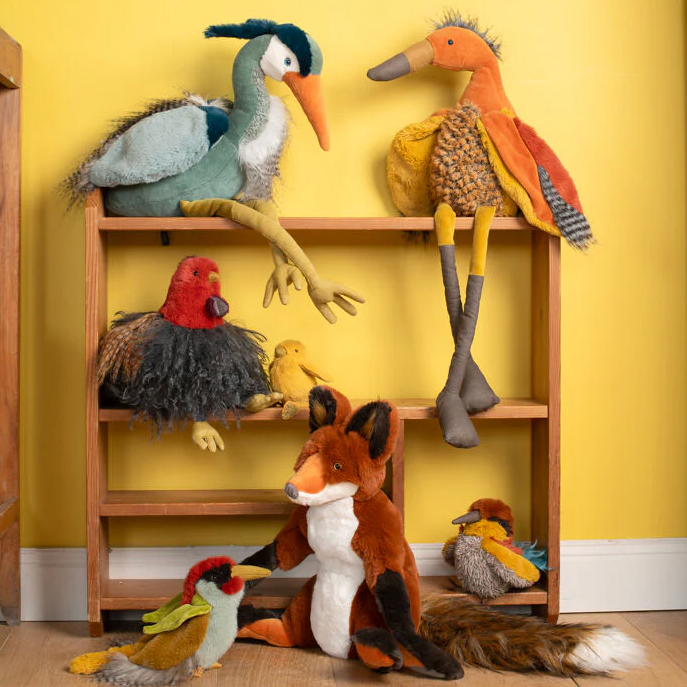 Collection of colorful stuffed animals on a wooden shelf against a yellow wall.