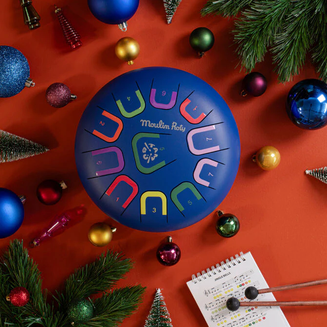 Colorful musical instrument on a festive background with Christmas ornaments and a notepad.