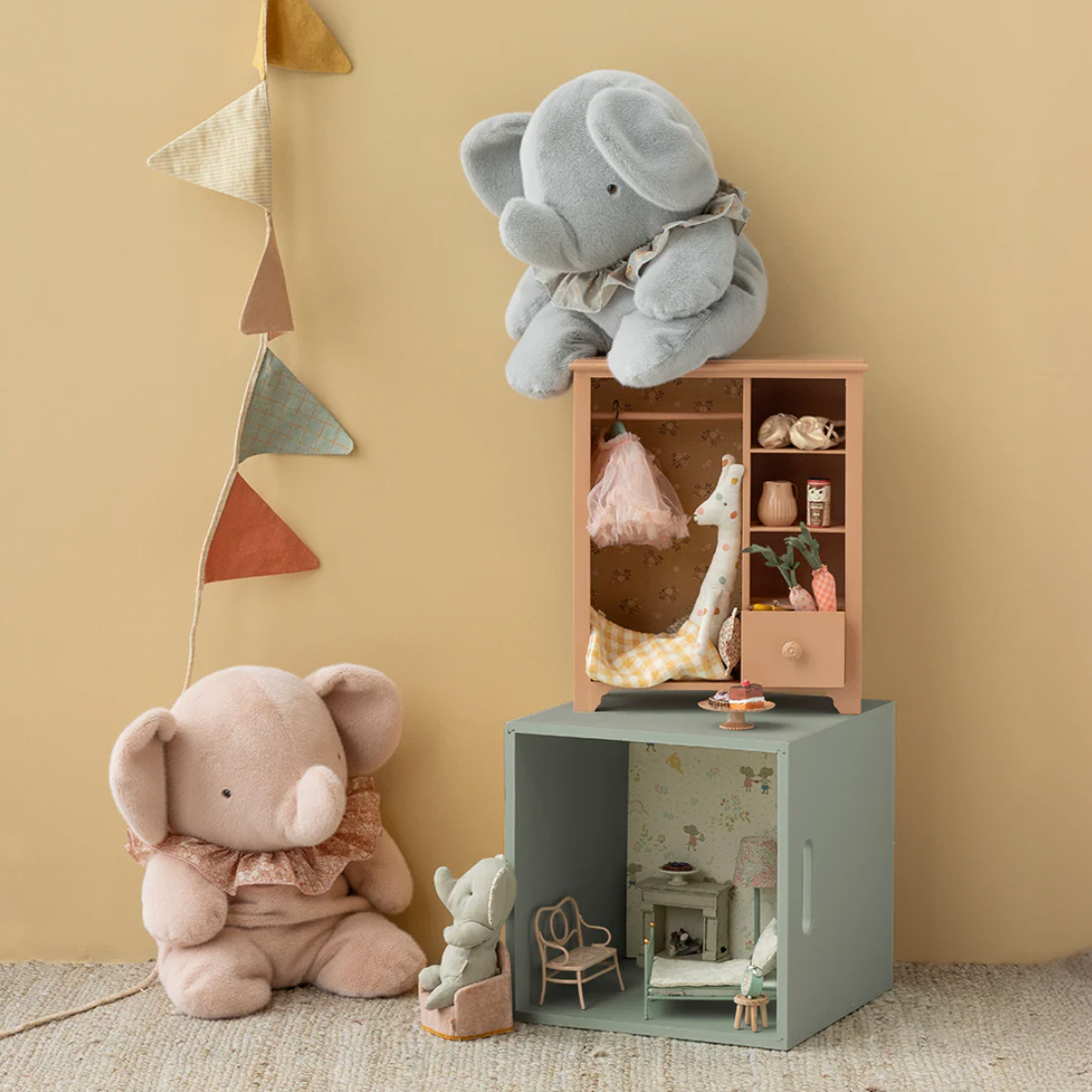 Children's room with plush elephant toys and a small wooden cabinet.