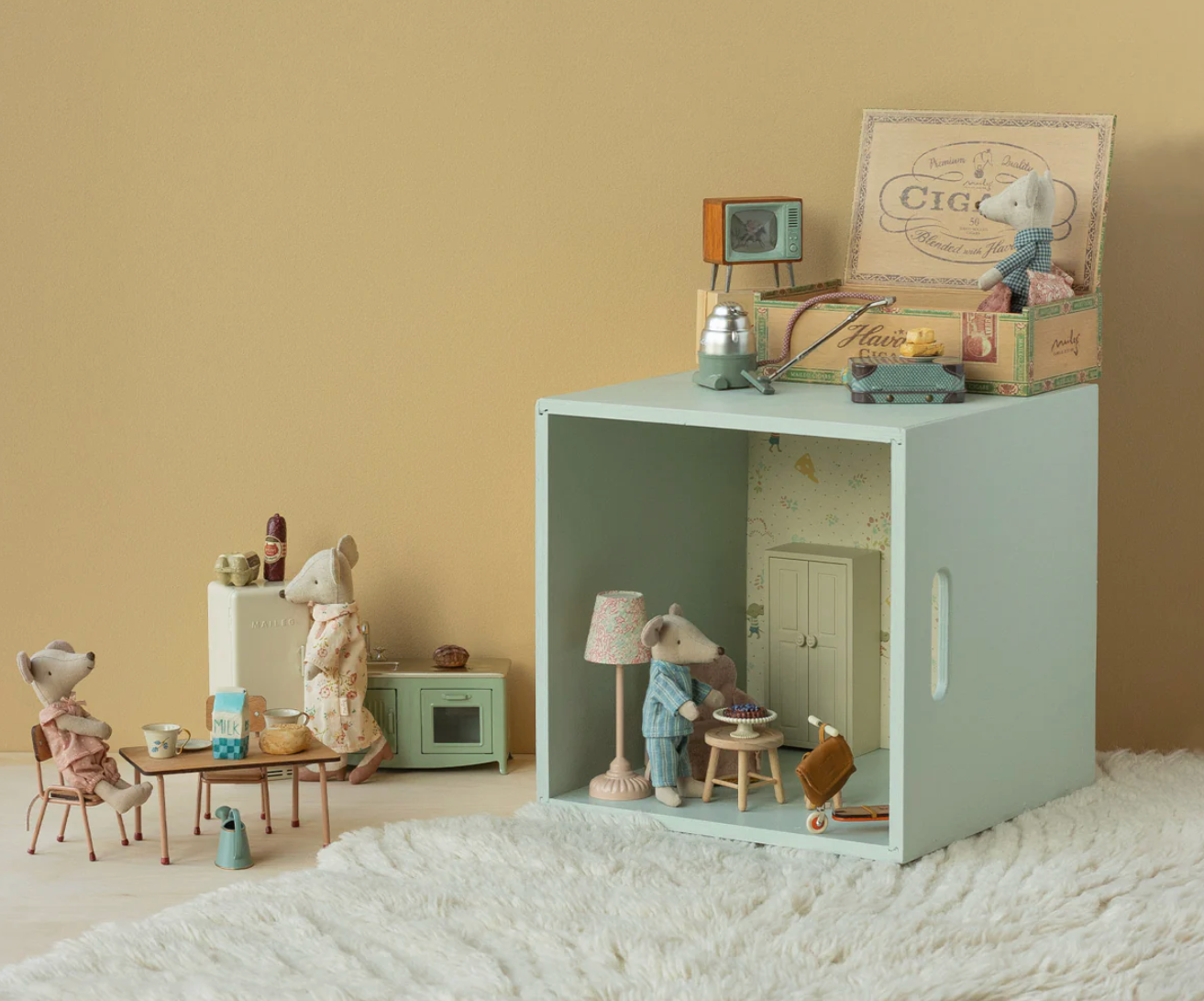 Miniature room setup with toys and furniture on a textured surface.