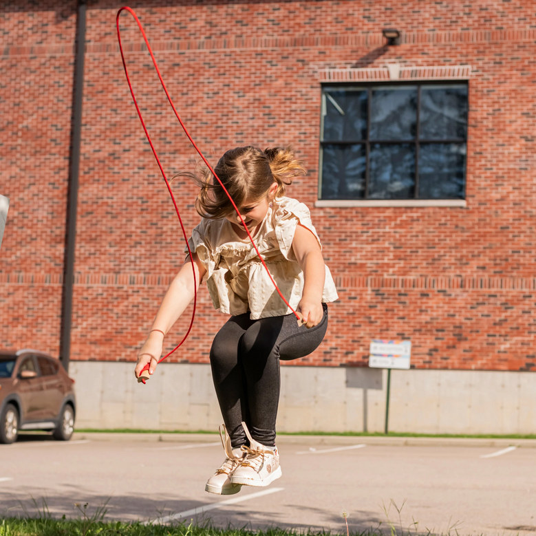 Child jumping rope in front of a brick building