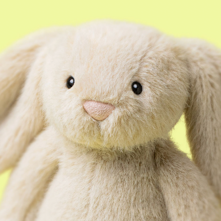 Plush bunny toy with a soft beige color on a yellow background