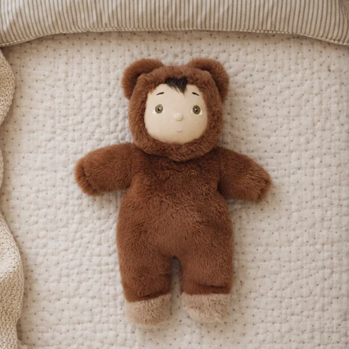 Brown plush toy with a face on a textured beige surface