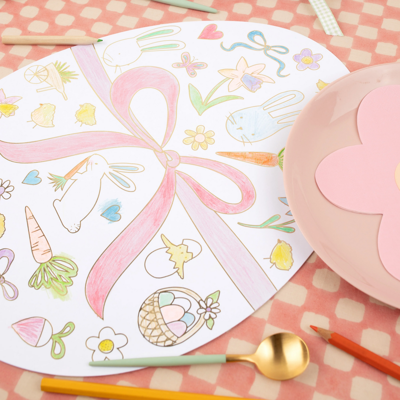 Coloring book with Easter-themed illustrations on a pink checkered tablecloth.