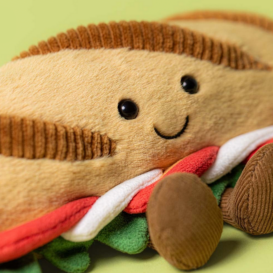 Plush toy resembling a sandwhich with a smiley face on a green background