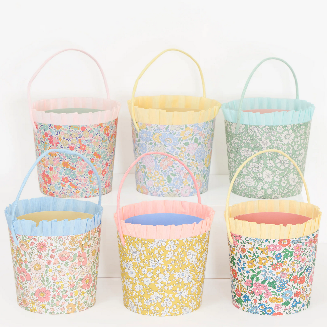 Set of colorful fabric buckets with floral patterns on a white background