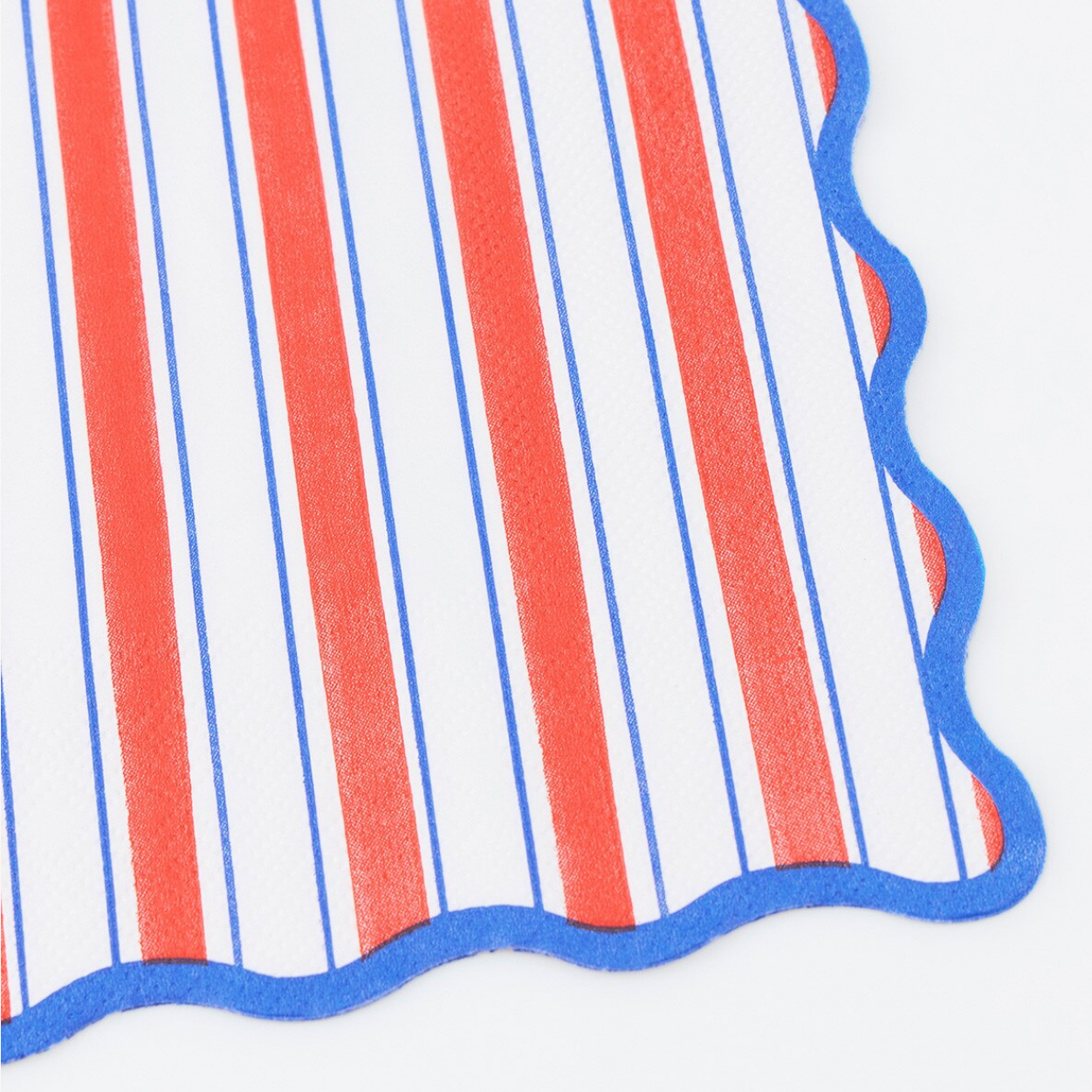 Close-up of a red, white, and blue striped fabric with scalloped edge on a white background